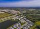 Aerial view of neighborhood and home near a tranquil lake with blue skies on a sunny day at 3704 Wild Blossom Pl, Parrish, FL 34219