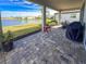 Covered outdoor patio featuring a brick floor, lake view, and outdoor furniture at 3704 Wild Blossom Pl, Parrish, FL 34219