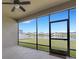 Covered patio with screened enclosure overlooking the serene pond and manicured lawn at 452 Tierra Verde Way, Bradenton, FL 34212