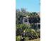 Exterior view of a home with a balcony, partially obscured by trees and tropical vegetation at 5649 Key Largo Ct, Bradenton, FL 34203