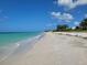 A serene beach with blue skies, calm turquoise water, and soft white sand at 618 Jungle Queen Way, Longboat Key, FL 34228