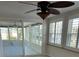 Bright sunroom with windows, plantation shutters, sliding glass door with access to a patio, tile floor, and ceiling fan at 618 Jungle Queen Way, Longboat Key, FL 34228