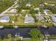 Aerial view of a waterfront home with a screened pool and lush landscaping along the canal at 9008 Allapata Ln, Venice, FL 34293
