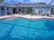 Screened-in pool area with an in-ground pool, patio furniture, and lush landscaping and plant decoration at 9008 Allapata Ln, Venice, FL 34293