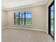 Bedroom with neutral walls and tile flooring showcases large window with views of the golf course at 10612 Nicklaus Ct, Englewood, FL 34223