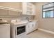 Bright laundry room with washer and dryer, built-in cabinets, and tile floors at 10612 Nicklaus Ct, Englewood, FL 34223