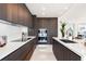 Sleek modern kitchen with dark wood cabinetry, stainless steel appliances, and white countertops at 111 Golden Gate Pt # 401, Sarasota, FL 34236