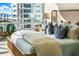Comfortable bedroom featuring a plush bed with blue accent pillows and stunning city views from large windows at 111 Golden Gate Pt # 401, Sarasota, FL 34236