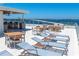 This rooftop deck features an outdoor kitchen, dining tables, lounge chairs, and stunning water views at 111 Golden Gate Pt # 401, Sarasota, FL 34236