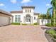 Stunning Mediterranean-style home featuring a paver driveway, lush landscaping, and a custom garage at 11740 Rive Isle Run, Parrish, FL 34219