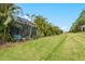 Green backyard featuring a screened-in patio area bordered with bushes and palm trees at 3922 Wildgrass Pl, Parrish, FL 34219
