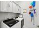Bright laundry room with upper cabinets and new-model washer and dryer at 3922 Wildgrass Pl, Parrish, FL 34219