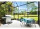 Covered patio with grill, dining table set, and lush green lawn view through screened enclosure at 3922 Wildgrass Pl, Parrish, FL 34219