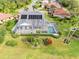 Aerial view of a home featuring solar panels and a screened-in pool in a lush, green setting at 6170 Misty Oaks Dr, Sarasota, FL 34243
