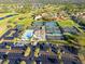 Aerial view of community with pool, tennis courts and ample parking surrounded by lush landscaping and nearby homes at 6170 Misty Oaks Dr, Sarasota, FL 34243