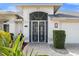 Up close exterior of entrance door with decorative screen door, stone pavers and professional landscaping at 6170 Misty Oaks Dr, Sarasota, FL 34243