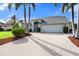 Attractive single-story home featuring an attached two-car garage, a landscaped yard, and mature palm trees at 6170 Misty Oaks Dr, Sarasota, FL 34243