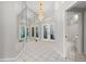 Bright foyer featuring a mirrored wall, decorative chandelier, and white tile flooring, leading to the front doors at 6170 Misty Oaks Dr, Sarasota, FL 34243
