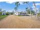 Charming home exterior featuring a gravel driveway, a quaint porch, and lush tropical landscaping at 624 Norsota Way, Sarasota, FL 34242