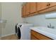 A well-lit laundry room with upper cabinets, sink, washer and dryer at 7315 Bianco Duck Ct, Sarasota, FL 34240