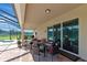 Covered patio with a brick floor, an outdoor dining set, and view of the screened pool and pond at 7315 Bianco Duck Ct, Sarasota, FL 34240