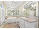 Bright bathroom with a marble counter, white cabinets, tiled floors, and a soaking tub at 3930 Red Rock Way, Sarasota, FL 34231