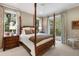 Well-lit bedroom with unique poster bed, wood furnishings, and balcony view of a lush landscaped garden at 3930 Red Rock Way, Sarasota, FL 34231