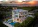 Stunning three-story coastal home featuring private pool, rooftop terrace, and beautiful architectural details at sunset at 630 Companion Way, Longboat Key, FL 34228