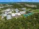 An aerial view of a school and tennis courts surrounded by green space and a water body in the distance at 790 Shadow Bay Way, Osprey, FL 34229