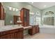 Bathroom featuring dual sinks, vanity, soaking tub, arched windows, and decorative fixtures at 790 Shadow Bay Way, Osprey, FL 34229