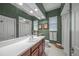 Stylish bathroom with a spacious countertop, framed mirror, and green accent wall at 790 Shadow Bay Way, Osprey, FL 34229