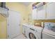 Bright laundry room features a utility sink, overhead cabinets and a washing machine at 790 Shadow Bay Way, Osprey, FL 34229