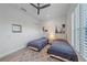 Bright bedroom with two twin beds, ceiling fan, neutral walls and a decorative rug at 328 Aria Dr, Nokomis, FL 34275