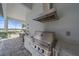 An outdoor kitchen with stainless steel appliances on a screened patio overlooking the backyard at 328 Aria Dr, Nokomis, FL 34275