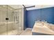 Bathroom featuring a glass enclosed shower with a dual sink vanity area and bold blue accent wall at 111 S Pineapple Ave # 708, Sarasota, FL 34236