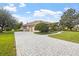 Expansive brick driveway leads to a well-maintained home with a lush lawn and mature trees at 2611 Little Country Rd, Parrish, FL 34219