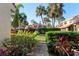 Landscaped front yard with brick walkway, lush plants, and palm trees creating curb appeal at 5343 Huntingwood Ct # 33, Sarasota, FL 34235