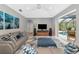 Bright living room with comfortable seating, modern entertainment center, and sliding glass doors to the screened-in pool area at 16806 5Th Ne Ter, Bradenton, FL 34212
