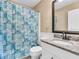Bathroom with gray granite countertop, white cabinetry, and a shower with patterned curtain at 1382 Ronald St, North Port, FL 34286