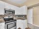 Modern kitchen with stainless steel appliances, granite countertops, and mosaic backsplash at 1382 Ronald St, North Port, FL 34286