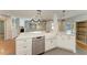 Kitchen island features a stainless steel dishwasher, white cabinets, a white farmhouse sink, and marble countertops at 2299 Riverwood Ct, Sarasota, FL 34231