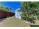 Blue shed in backyard surrounded by a wood fence, grass and a mature tree at 2299 Riverwood Ct, Sarasota, FL 34231