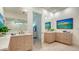 Bright bathroom with double sink vanity, modern lighting, and beach-themed artwork, enhanced by neutral stone flooring at 3178 Dick Wilson Dr, Sarasota, FL 34240