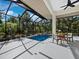 Beautiful screened pool with a waterfall feature and outdoor table and chairs for lounging at 3178 Dick Wilson Dr, Sarasota, FL 34240