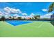 View of two green and blue tennis courts surrounded by trees and shrubbery on a sunny day at 20296 Bandera Pl, Venice, FL 34293