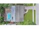 Aerial view of a house featuring a screened-in pool, patio, and brick driveway with lush greenery around the property at 2264 Floyd St, Sarasota, FL 34239