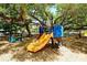 A playground with a yellow slide and blue climbing structure sits beneath a large shade tree at 2264 Floyd St, Sarasota, FL 34239