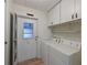 Bright laundry room with white appliances, cabinets, and convenient exterior access door at 4531 13Th E St, Ellenton, FL 34222