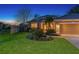 Charming home featuring a well-kept lawn, colorful garden, and a three-car garage under a twilight sky at 5401 Oak Grove Ct, Sarasota, FL 34233