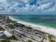 Expansive aerial view of a pristine beach with turquoise water, parking and nearby buildings under a cloudy sky at 800 S Blvd Of Presidents # 12, Sarasota, FL 34236